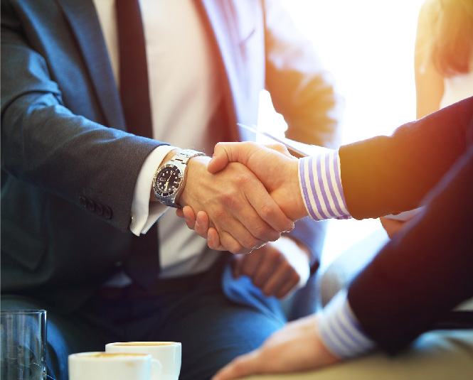 Two nicely dressed men shaking hands.