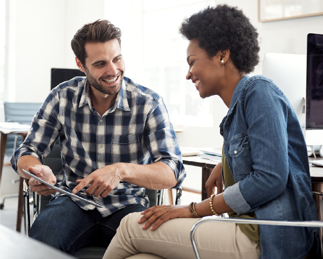 Young man and woman looking at a tablet, smiling.